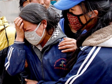 Mulher chora ao ver o corpo do filho ser retirado de escombros de uma escola, durante as buscas em Yushu