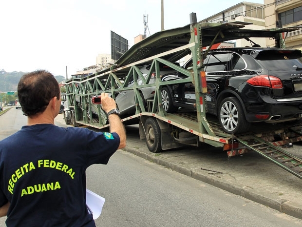 Agente da Receita Federal fotografa carros importados apreendidos em operao da Polcia Federal na Barra da Tijuca, Zon