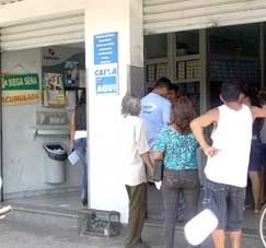 Clientes esperam na fila para serem atendidos em uma casa lotrica de Cuiab