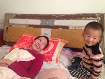 Gao Qianbo, de 2 anos, faz a me rir; garoto fica o dia todo ao lado da me acamada.