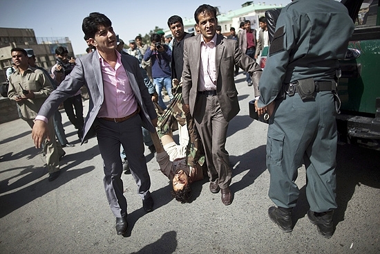 Policiais a paisana carregam corpo de um dos criminosos que invadiu uma delegacia de polcia em Cabul