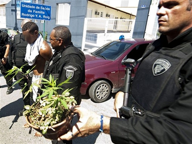 Policiais escoltam um suspeito de trfico e levam vaso de maconha