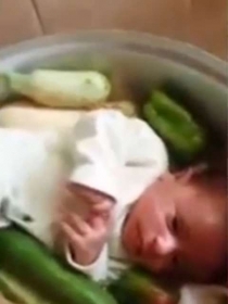 Quando o pai da criana abre a panela, um beb  visto ao lado de legumes