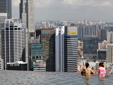 Hspedes do hotel Marina Bay Sands, em Cingapura, observam a cidade de uma piscina com lateral que termina em queda d'gua, no topo do edifcio.