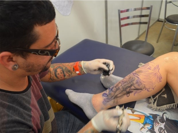 O tatuador Gluber marca a pele da amiga com uma caricatura do Pe Lanza