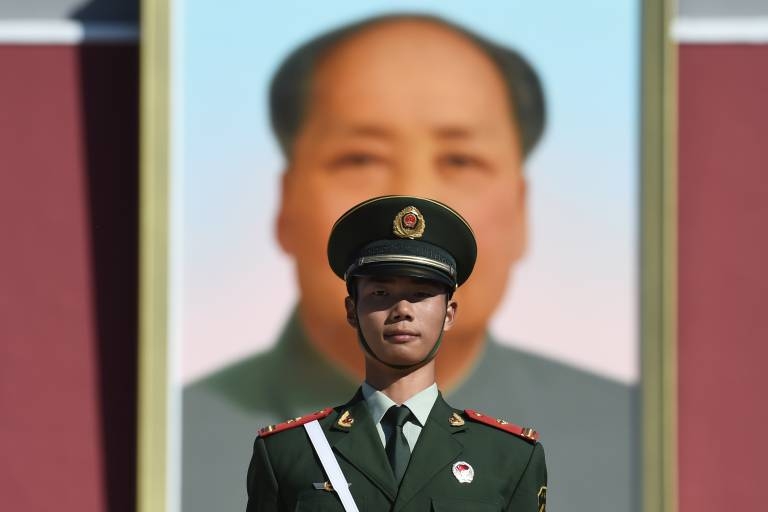 Policial monta guarda diante de retrato do ditador comunista chins Mao Tse Tung (Greg Baker/AFP)