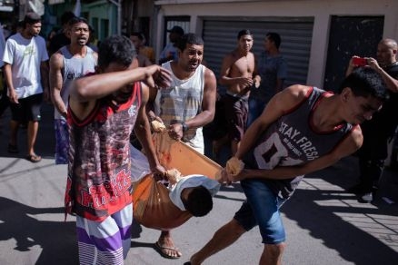 Homem é carregado por moradores após operação policial no Complexo do Alemão, na zona norte do Rio