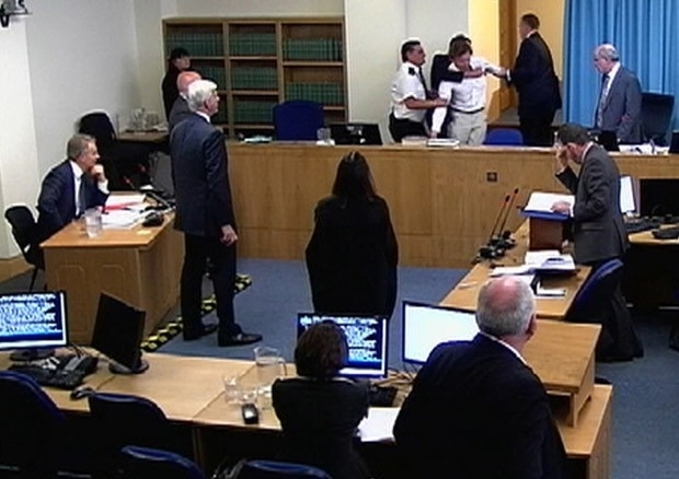Imagem de TV mostra o manifestante sendo retirado por seguranas durante depoimento de Tony Blair (sentado  esquerda)