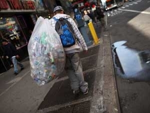 Jovem recolhe latas em Nova York, em foto de arquivo