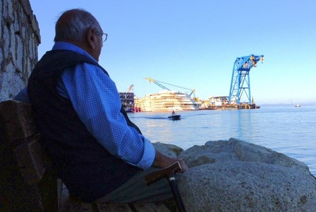 Homem observa, a partir da ilha italiana de Giglio, os trabalhos no naufragado navio Costa Concordia, nesta tera-feira