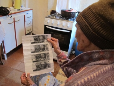 A aposentada Madalena, que no quis mostrar o rosto, v a cpia das notas retidas feita pelo banco 