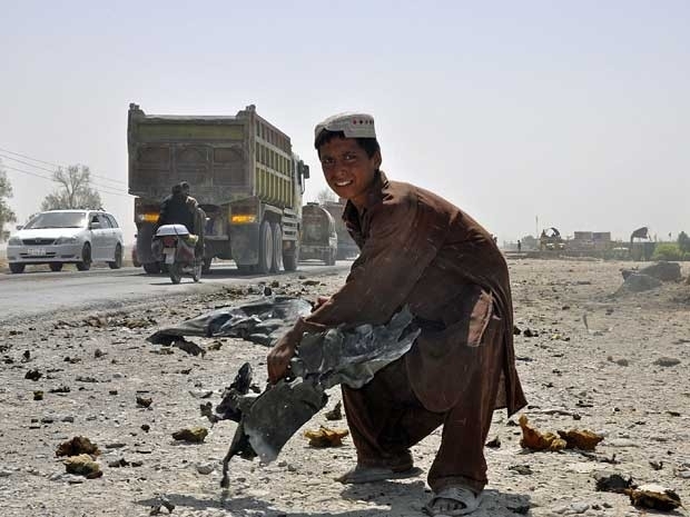 Criana afeg levanta um destroo de um veculo no local de um ataque suicida em Kandahar.