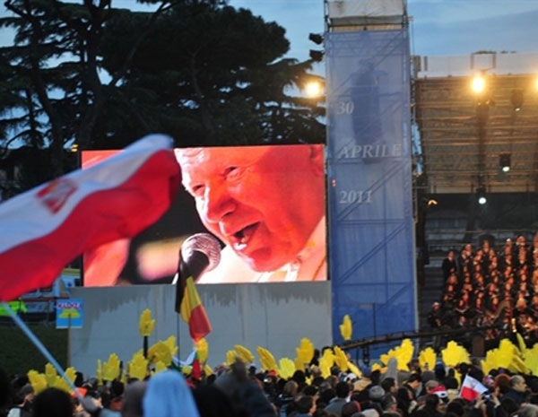 Peregrinos se renem em frente a uma tela que mostra imagens do Papa Joo Paulo II, em Roma