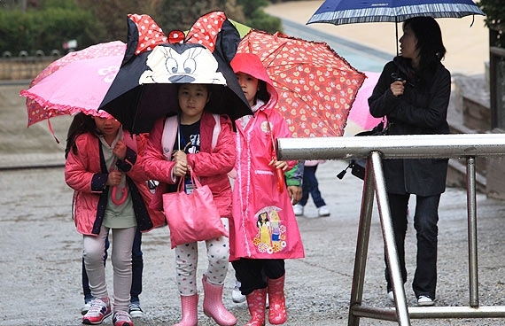 Crianas voltam para casa depois que a escola elementar de Midong fechou por causa da chuva