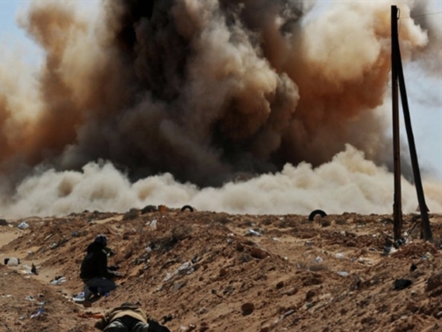 Rebeldes protegem-se durante bombardeio  regio prxima a Ras Lanuf nesta segunda-feira (7) na Lbia